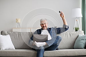 Relaxed man sitting on couch with laptop, turn on AC