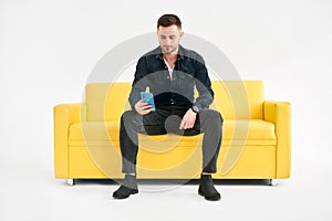 Relaxed man sitting on couch using hsi mobile phone