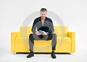 Relaxed man sitting on couch using hsi mobile smart phone