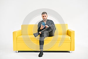 Relaxed man sitting on couch using hsi mobile smart phone