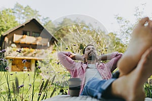 Relaxed man sitting in the garden with feet on table. Father having moment to himself while his kids are in school.