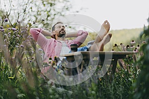 Relaxed man sitting in the garden with feet on table. Father having moment to himself while his kids are in school.