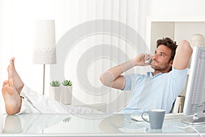 Uvolněná muž mluvení na mobilní telefon na psací stůl 