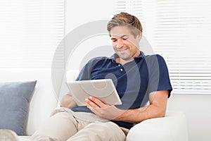Relaxed man using digital tablet in living room