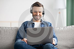 Relaxed man watching movie, using laptop and headphones