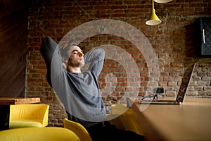 Relaxed mature businessman reclining at lobby on laptop