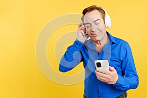 Relaxed mature man listening to music with headphones and mobile