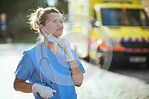 Relaxed medical doctor woman breathing outdoors near ambulance