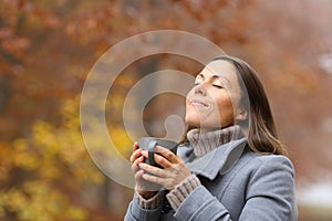 Relaxed middle age woman with coffee breathing in fall