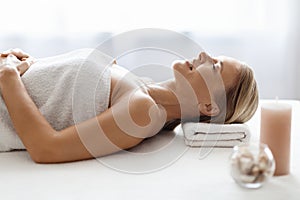 Relaxed Middle Aged Woman Lying On Table In Spa Salon, Side View