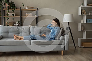 Relaxed millennial smiling woman using computer at home.