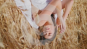 Relaxed model chilling sunny hay land vertical. Meditative woman lay sun field