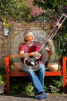 Relaxed older man is playing a sitar