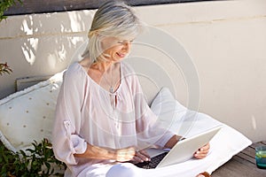 Relaxed older woman outside with laptop