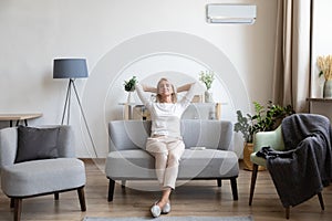 Relaxed older woman sitting on couch in air conditioner room