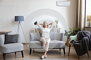 Relaxed older woman sitting on couch in air conditioner room photo