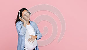 Relaxed pregnant woman listening to calm music and smiling