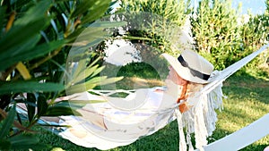 relaxed senior woman in straw hat smiling happy relaxing on a hammock enjoying the fresh air on the terrace around the