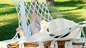 relaxed senior woman in straw hat smiling happy relaxing on a hammock enjoying the fresh air on the terrace around the