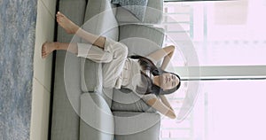 Relaxed sleepy young Chinese woman resting on comfortable couch