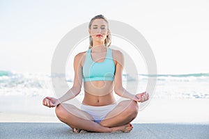 Relaxed slender blonde in sportswear meditating