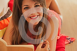 Relaxed smiling woman, reading lying on the floor