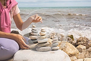 Relaxed spiritually woman hand arrangement pebble tower cobblestone sea coastline landscape closeup photo