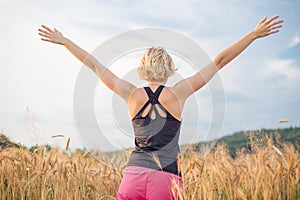 Relaxed sporty woman, arms rised, enjoying nature in the beautifull morning at wheet field.