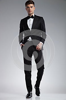 Relaxed stylish man wearing a black tuxedo walking