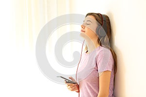 Relaxed teen listening to music on leaning a wall
