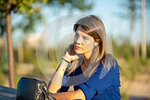 Relaxed and thoughtful woman sitting outdoors in a park
