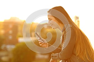 Relaxed woman in a balcony checking smart phone