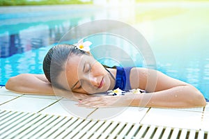 Relaxed woman in blue dress in the pool, eyes closed