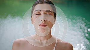 Relaxed woman breathing deeply doing yoga exercise at turquoise lake closeup