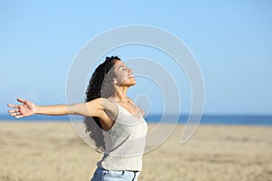 Relaxed woman breathing with open arms on the beach