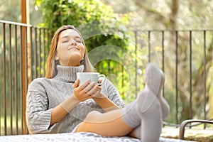 Relaxed woman with coffee mug resting in a balcony