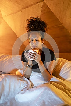 Relaxed woman drinking coffee in bed.