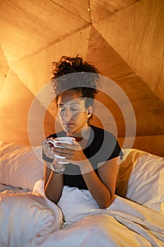 Relaxed woman drinking coffee in bed.