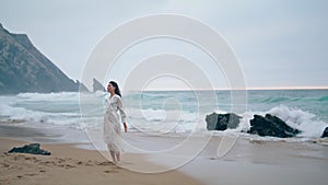 Relaxed woman enjoy stormy seascape at cloudy weekend. Girl moving body on beach