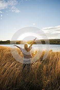 Relaxed woman enjoying fresh air at windy lake during autumn sunset