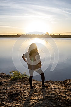 Relaxed woman enjoying the sunset standing outdoors at a lake.