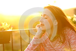 Relaxed woman feeling in a balcony at sunset