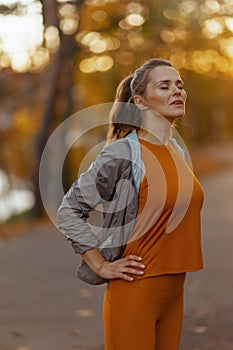 relaxed woman in fitness clothes in park relaxing