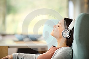 Relaxed woman with headphones listening to music on a sofa