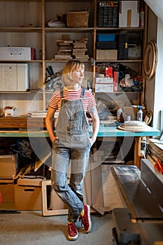 Relaxed woman joiner spending time at workplace take break in carpentry workshop looking at window.