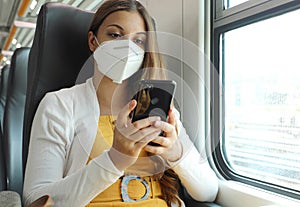 Relaxed woman with KN95 FFP2 face mask using smart phone app. Train passenger with protective mask traveling sitting in business