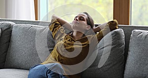 Relaxed woman lean on sofa cushions resting alone at home