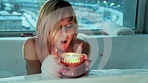 Relaxed woman lighting a candle while taking a bubble bath in the evening.