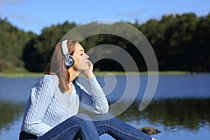 Relaxed woman listening to music with headphones in a lagoon