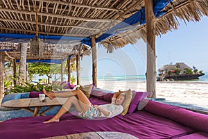 Relaxed woman in luxury tropical bar lounger, enjoying summer vacations on beautiful beach.